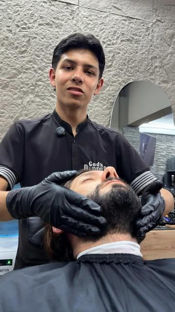 Masaje facial con guantes negros en God's Barber